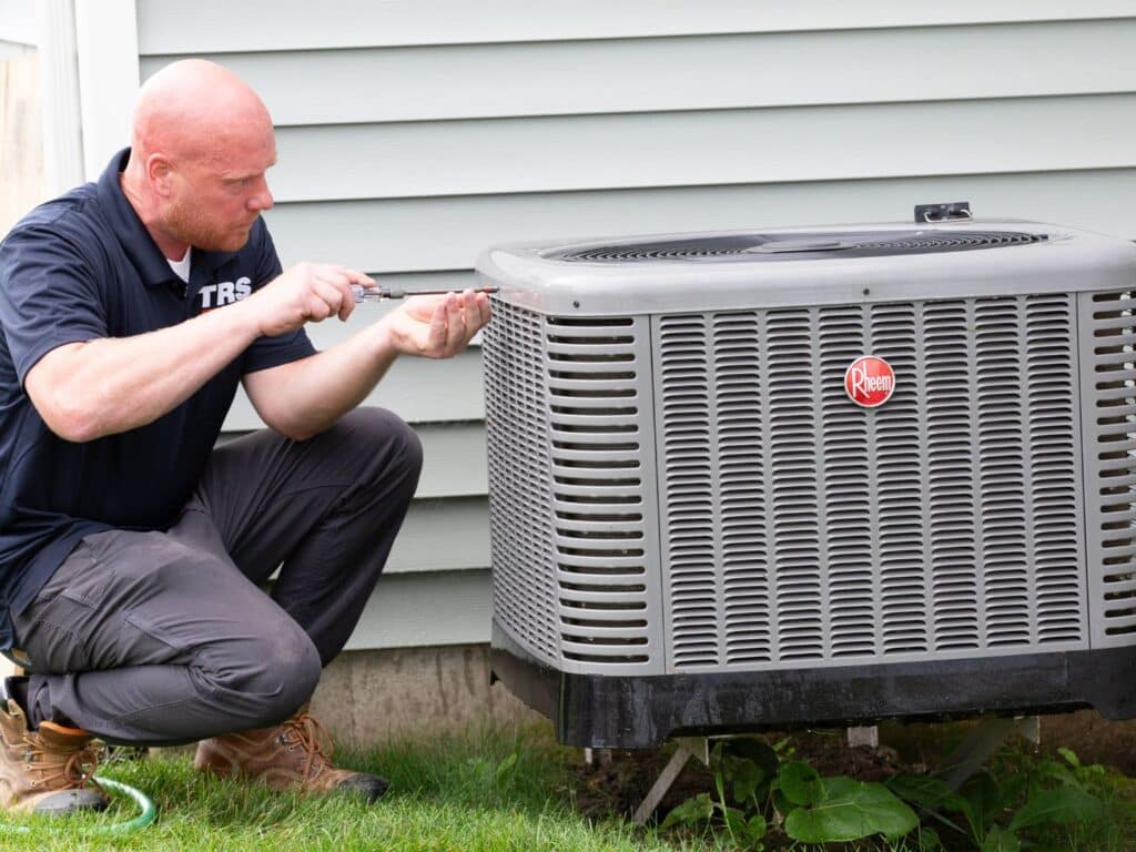 Technician completing air conditioner repair at Cheektowaga residence.