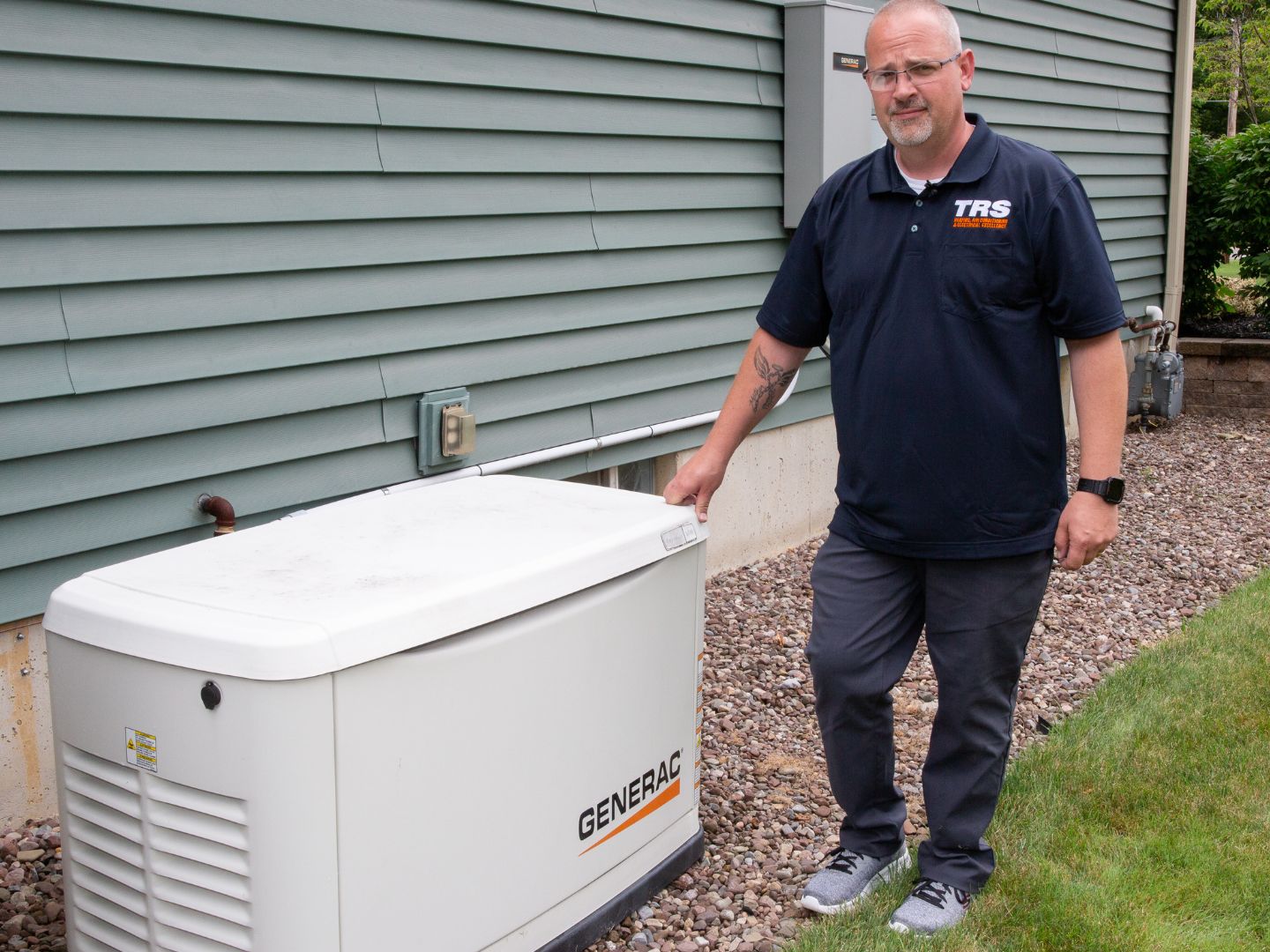 A technician standing next to a generator connected to a ductless AC system in a home.